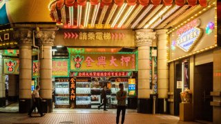 Pedestrians in front of a pawn shop during Golden Week at night in Macau, China, on Sunday, April 30, 2023.