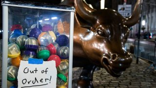 Artist Nelson Saiers installs his latest “Cheap Money No. 2” sculpture at “The Wall Street Bull” on December 07, 2021 in New York City.