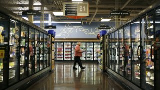 A customer walks past the frozen food aisle inside a Kroger Co. grocery store in Louisville, Kentucky.