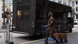 A UPS driver pulls a cart up to his truck while making deliveries on June 12, 2023 in San Francisco, California.
