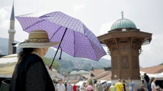 A woman holds an umbrella to avoid sunrays due to high temperatures in the city center of Sarajevo, Bosnia and Herzegovina on July 06, 2023.