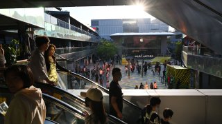 People ride an escalator at a shopping mall in Beijing on the second day of a holiday in late April 2023.