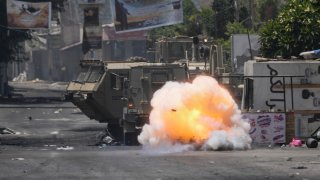 A bomb thrown by a Palestinian explodes next to an Israeli army vehicle during a military raid in the Jenin refugee camp, a militant stronghold, in the occupied West Bank, Tuesday, July 4, 2023. Palestinian health officials said at least 10 Palestinians were killed and dozens wounded in the operation, which began Monday.