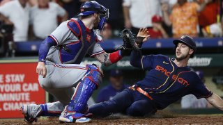 HOUSTON, TEXAS – JULY 24: Kyle Tucker #30 of the Houston Astros slides by Jonah Heim #28 of the Texas Rangers for the winning run in the ninth inning at Minute Maid Park on July 24, 2023 in Houston, Texas.