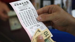 CHICAGO, IL – AUGUST 07:  A customer at a 7-Eleven store checks the numbers on his Powerball lottery ticket on August 7, 2013 in Chicago, Illinois. The Powerball jackpot for tonight’s drawing is $425 million, the third-highest total ever.  (Photo by Scott Olson/Getty Images)