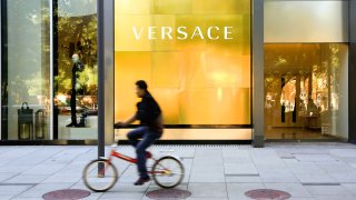 A man rides a bicycle past a Gianni Versace store in Beijing, China.