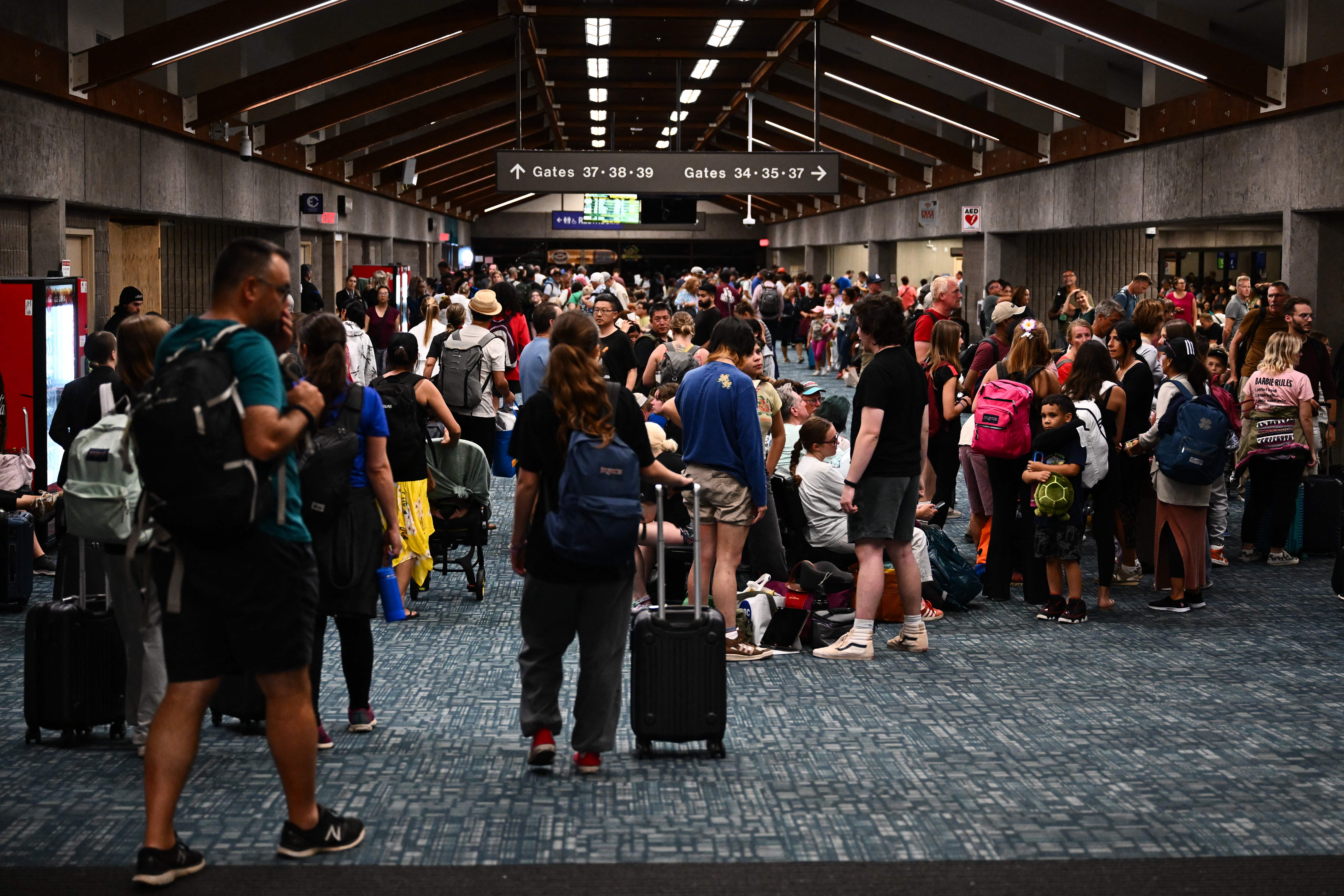 Passengers try to rest and sleep after canceled and delayed flights while others wait to board flights off the island as thousands of passengers were stranded at the Kahului Airport in the aftermath of wildfires in Maui in Kahului, Hawaii, Aug. 9, 2023.