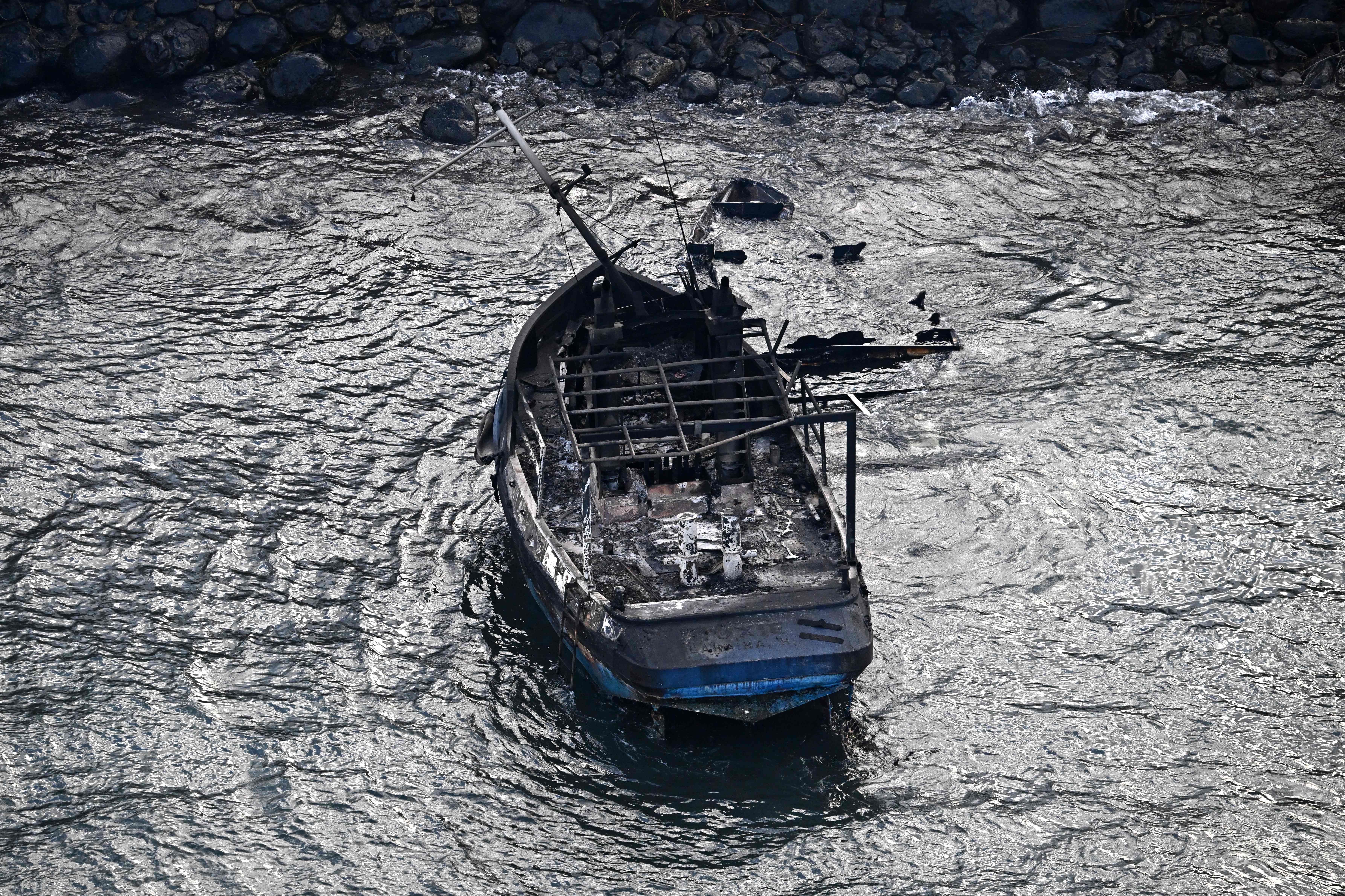 A charred boat sits in Lahaina Harbor in the aftermath of wildfires in western Maui, Hawaii.