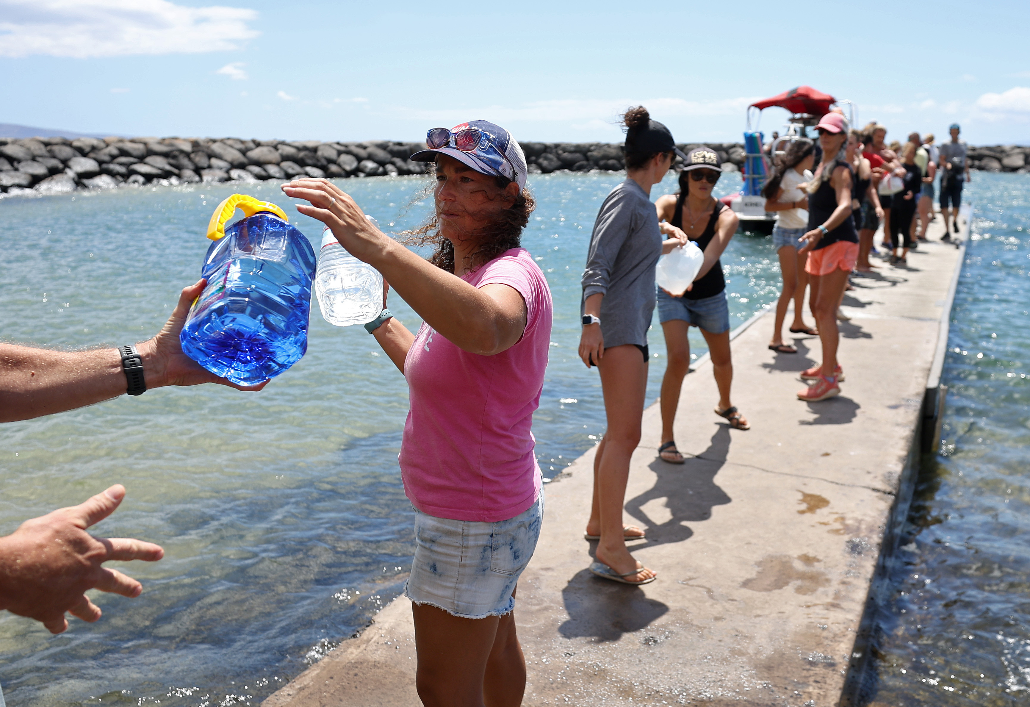 Volunteers load water onto a boat to be transported to West Maui from the Kihei boat landing on Aug. 13, 2023, in Kihei, Hawaii. At least 93 people were confirmed dead over the weekend, and thousands were displaced after a wind driven wildfire devastated the towns of Lahaina and Kula this past week. Crews are continuing to search for nearly 1,000 missing people.