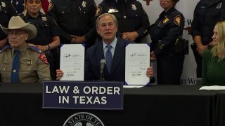 Greg Abbott holds up signed bills.