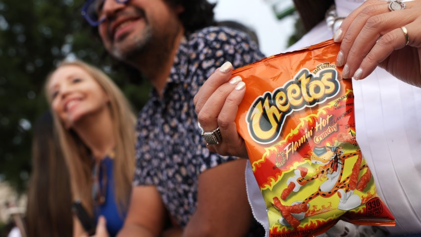 A woman holds a bag of Flamin' Hot Cheetos