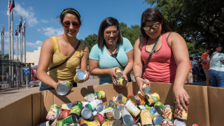 3 women donating canned food to the North Texas Food Bank at the State Fair of Texas.