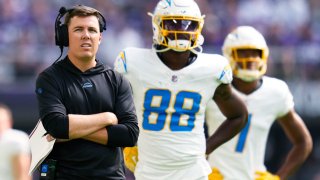 FILE – Los Angeles Chargers offensive coordinator Kellen Moore, left, stands on the field during the first half of an NFL football game against the Minnesota Vikings on Sept. 24, 2023, in Minneapolis. Moore has been under the spotlight since he was named the Los Angeles Chargers offensive coordinator in late January. (AP Photo/Abbie Parr, File)