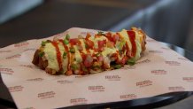 Chefs at Dallas's American Airlines Center show off new menu items for fans attending events in the 2023-24 season. Shown, the Chimichanga hotdog.