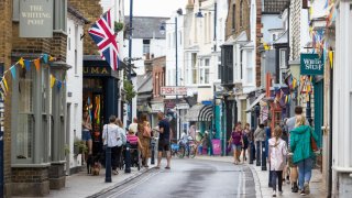 Shoppers pass along the main high street in Whitstable, UK.