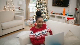 Beautiful African American female student sitting at home, working using her laptop during winter holidays