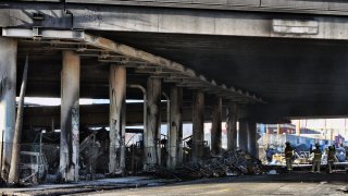Los Angeles firefighters mop up from a fire under Interstate 10