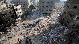 Palestinians look at destruction after an Israeli strike on the Gaza Strip in Nusseirat refugee camp, central Gaza Strip, Friday, Nov. 17, 2023.