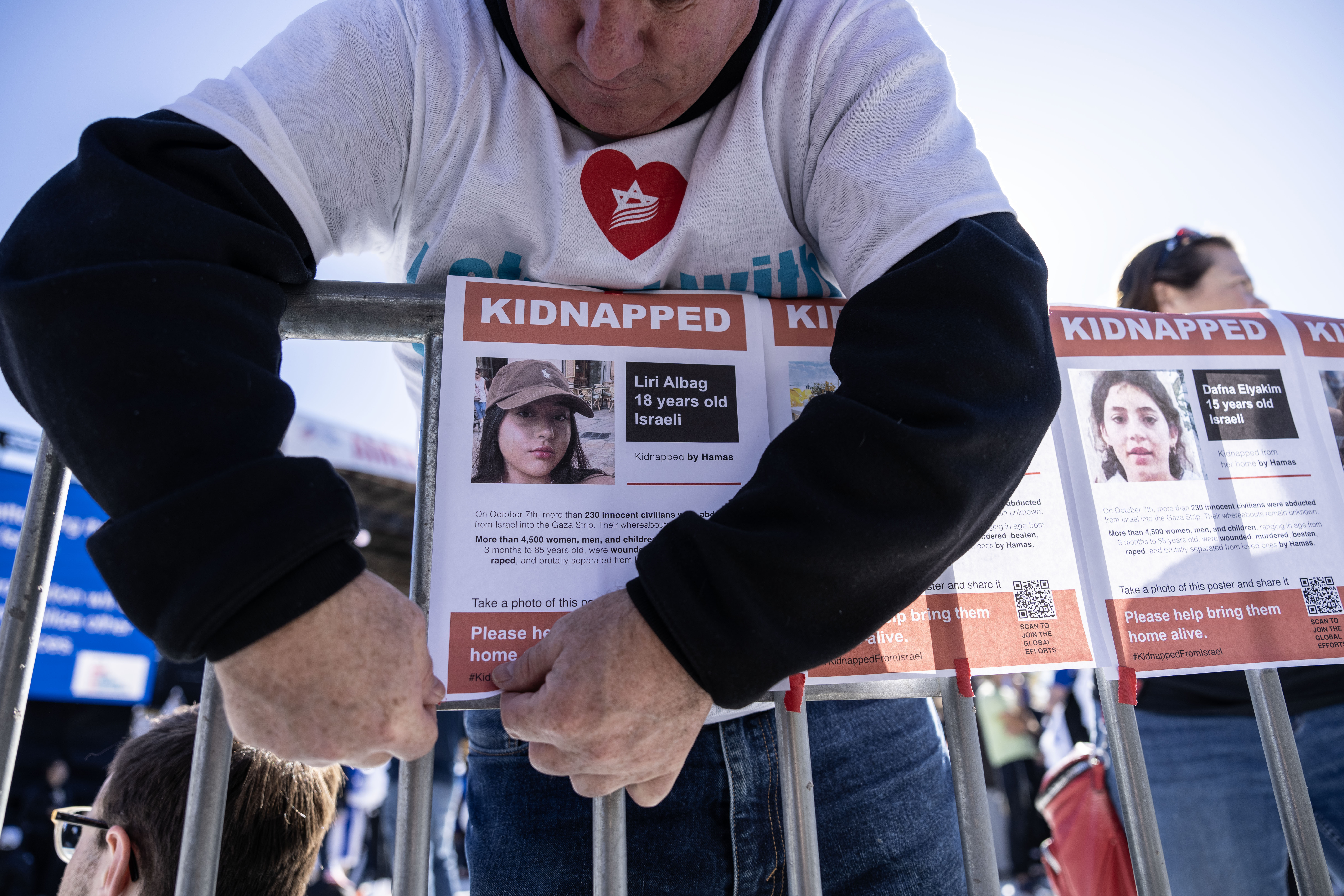 A man tapes up signs of hostages taken by Hamas during the March for Israel on the National Mall November 14, 2023 in Washington, DC.