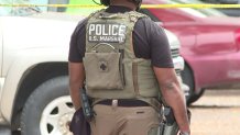 A member of a US Marshals Task Force stands outside a Dallas apartment complex after a shootout while serving a capital murder warrant, Thursday, Nov. 16, 2023.