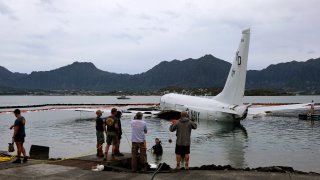 Contractors place inflatable bags under a U.S. Navy P-8A in Kaneohe Bay, Hawaii
