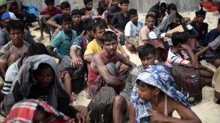 Ethnic Rohingya men sit on a beach after they landed in Sabang, Aceh province, Indonesia.