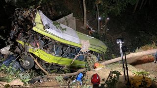 In this photo a rescuer rappels down a damaged passenger bus in a ravine at the mountainous Hamtic town, Antique province, central Philippines.