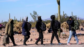 A group of migrants walk to a van as hundreds of migrants gather along the border Tuesday, Dec. 5, 2023, in Lukeville, Ariz. The U.S. Border Patrol says it is overwhelmed by a shift in human smuggling routes, with hundreds of migrants from faraway countries like Senegal, Bangladesh and China being dropped in the remote desert area in Arizona.