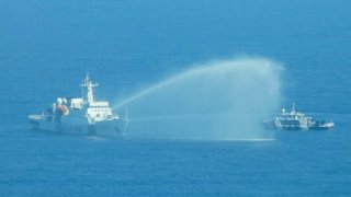 In this photo provided by the Philippine Coast Guard, a Chinese Coast Guard ship, left, uses its water cannons on a Philippine Bureau of Fisheries and Aquatic Resources (BFAR) vessel