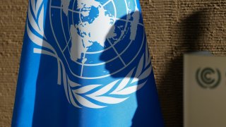 United Nations Climate Chief Simon Stiell’s shadow is visible on the U.N. flag as he speaks during a news conference at the COP28 U.N. Climate Summit, Monday, Dec. 11, 2023, in Dubai, United Arab Emirates.