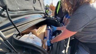 Volunteers with the Tarrant Area Food Bank load food into a car during a food distribution at Dickies Arena in December 2023.