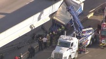 Deputies with the Dallas County Sheriff's Office work to free a truck hanging off a bridge, Monday, Dec. 4, 2023.