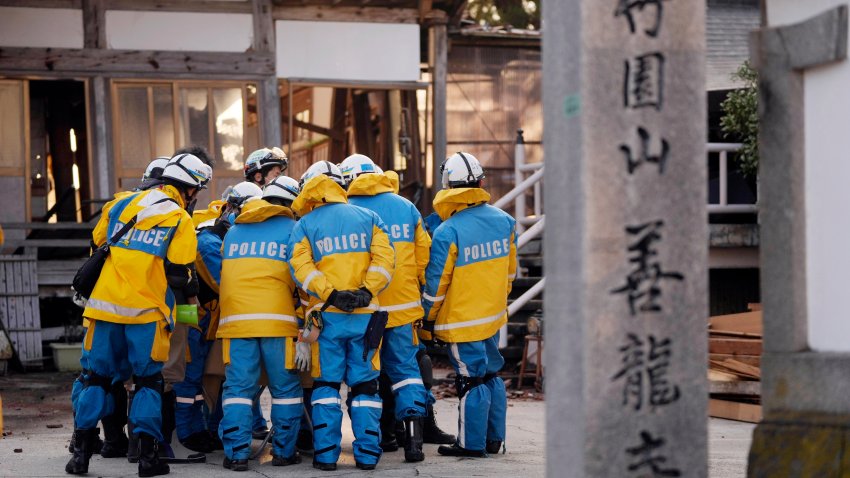 Police officers huddle up before getting into a building at the premises of a temple