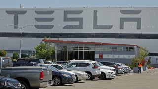 A man walks in the Tesla plant parking lot, May 11, 2020, in Fremont, Calif. Factory workers at Tesla have been told to expect pay raises in 2024, a move that comes as the United Auto Workers union tries to organize the electric vehicle maker’s U.S. plants. The UAW said Thursday, Jan. 11, 2024, that Tesla workers have told the union about company statements on the raises, which did not give details about the size of the increases.