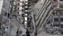 FILE - Palestinians walk through destruction in Gaza City on Friday, Nov. 24, 2023, as the temporary ceasefire between Israel and Hamas took effect. Now 100 days old, the latest Israel-Hamas war is by far the longest, bloodiest, and most destructive conflict between the bitter enemies. The fighting erupted on Oct. 7, 2023 when Hamas carried out a deadly attack in southern Israel. Since then, Israel has relentlessly pounded the Gaza Strip with airstrikes and a ground offensive that have wrought unprecedented destruction, flattening entire neighborhoods.