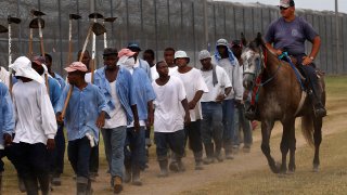 In this Aug. 18, 2011 photo, a prison guard rides a horse alongside prisoners as they return from farm work detail at the Louisiana State Penitentiary in Angola, La. After the Civil War, the 13th Amendment’s exception clause, that allows for prison labor, provided legal cover to round up thousands of mostly young Black men. They then were leased out by states to plantations like Angola and some of the country’s biggest privately owned companies, including coal mines and railroads. (AP Photo/Gerald Herbert)