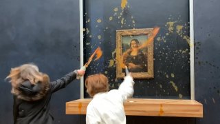 two environmental activists from the collective dubbed "Riposte Alimentaire" (Food Retaliation) hurling soup at Leonardo Da Vinci's "Mona Lisa" (La Joconde) painting, at the Louvre museum in Paris