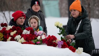 A woman lays flowers to pay the last respect to Alexei Navalny at the monument, a large boulder from the Solovetsky islands, where the first camp of the Gulag political prison system was established, near the historical the Federal Security Service (FSB, Soviet KGB successor) building in Moscow, Russia, on Sunday, Feb. 18, 2024. Russians across the vast country streamed to ad-hoc memorials with flowers and candles to pay tribute to Alexei Navalny, the most famous Russian opposition leader and the Kremlin's fiercest critic. Russian officials reported that Navalny, 47, died in prison on Friday.