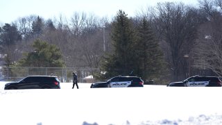 A police officer walks across a road after two police officers and a first responder were shot and killed Sunday, Feb. 18, 2024, in Burnsville, Minn.