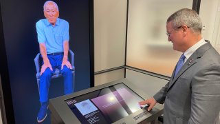 Peter Crean of the National WWII Museum in New Orleans stands at an interactive exhibit with an image of Japanese-American WWII veteran Lawson Ichiro Sakai.