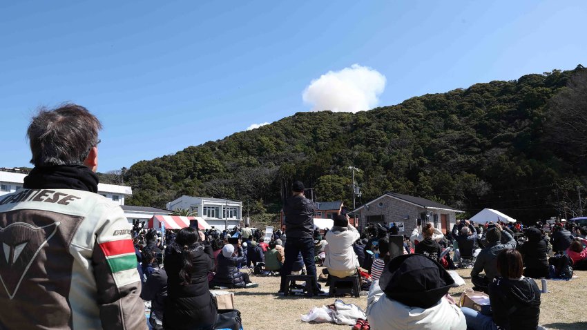 Visitors look on as smoke rises from behind a hill after a small rocket by Tokyo-based startup Space One exploded.