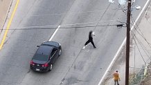 A man crosses Loop 12 and dodges cars near a DART bus stop.