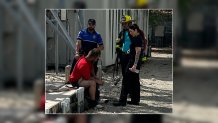 An image released by Miami Police shows a man who climbed a cell tower on the ground speaking with first responders.