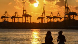 People sitting by a pier during sunset in Singapore.
