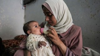 Rola Saqer feeds her baby Masa Mohammad Zaqout at her parents' home in the neighborhood of Zawaida, central Gaza, Thursday, April 4, 2024. Zaqout was born Oct. 7, the day the Israel- Hamas war erupted. Mothers who gave birth that day fret that their 6-month-old babies have known nothing but brutal war, characterized by a lack of baby food, unsanitary shelter conditions and the crashing of airstrikes. (AP Photo/Abdel Kareem Hana)