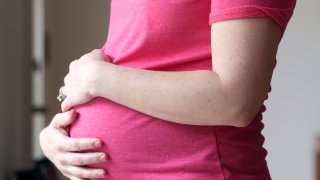 A pregnant woman stands for a portrait