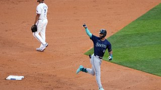 Seattle Mariners’ Julio Rodriguez celebrates his two-run home run as he jogs past Texas Rangers second baseman Marcus Semien during the third inning of a baseball game in Arlington, Texas, Tuesday, April 23, 2024.