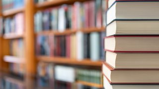 Many books stacked with blurred background of bookstore full of books. Photo with copyspace