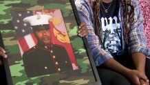 The family of Anthony Johnson holds up a photo of him in his Marine Corps dress blues.