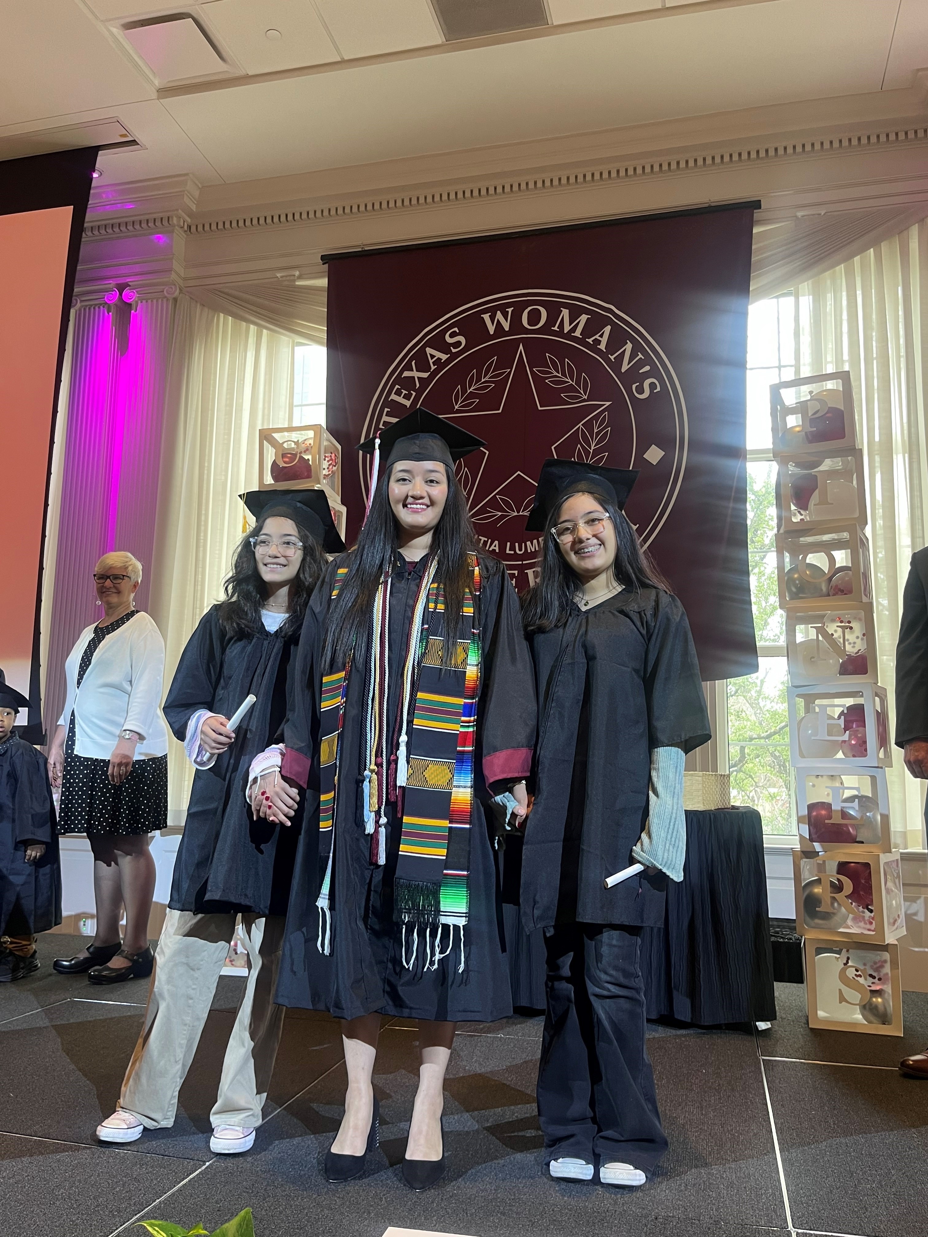 I want to share photos for possible inclusion in BRAG ABOUT YOUR GRAD. She’s a very dedicated woman who has persevered so much and will be receiving her college degree on May 11 from Texas Woman’s University.
35-year-old Gloria Aguilar is a single mom with two daughters, Evolet Zendejas 13 years old and Sofia Zendejas 10 years old. Her mom lives in Mexico and her dad lives in Kansas. She married a man and experienced domestic violence. After dealing with escaping the violence, living in a women’s shelter, divorce and custodial battles, she moved to Dallas to restart her life.
On April 27, she and her family participated in Family Graduation at Texas Woman’s University which allows the entire family to get involved with the graduation process, a unique feature at the school. Her formal graduation is on Saturday, May 11, 9am at Texas Woman’s University in Denton. She will be graduating with a B.S. in Family Studies. She is the first generation to graduate in her family, too!
Attached are photos of Gloria and her two daughters at TWU’s Family Graduation on April 27.